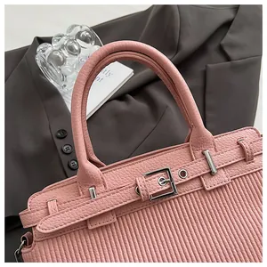 Dettaglio borsa rosa con texture plissettata e fibbia argento su blazer marrone