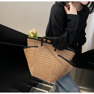 Close-up of woven straw tote bag featuring black PU handles and yellow interior lining