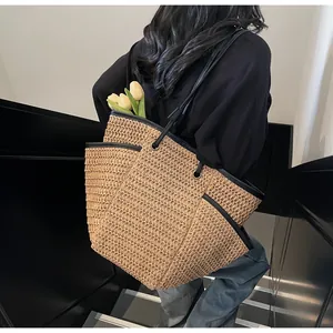 Macro shot of large woven straw tote bag with black leather trim and interior floral detail