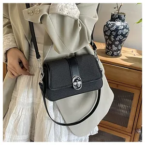Detail of black crossbody bag with woven texture, silver metal clasp, and matte leather finish