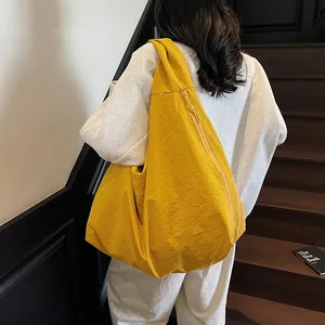 Large yellow hobo tote bag in lightweight nylon fabric worn by a model on stairs