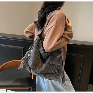 Detail of a large washed gray denim hobo bag featuring metallic rivets and retro street style