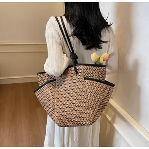 Detail of hand-woven straw tote with black leather trim and tulip flower accent