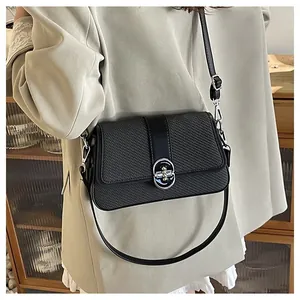 Detail of black woven shoulder bag featuring an oval silver metal turn-lock buckle