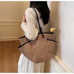 Close-up of large straw tote bag with black shoulder straps and practical side pocket