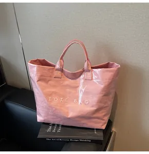 Detailed view of pink tote bag with embossed TOTE BAG lettering and crinkled texture