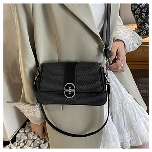 Detail of black woven texture crossbody bag with silver oval metal buckle on khaki suit