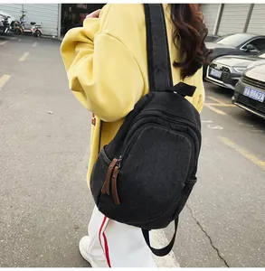 Detail of black washed denim backpack showing side view with leather pullers on zippers