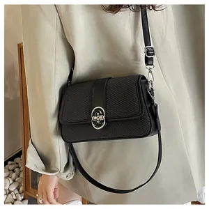 Detail of black crossbody bag featuring textured synthetic leather and silver oval lock