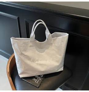 Detailed view of a white tote bag with unique crinkled texture on a black leather chair