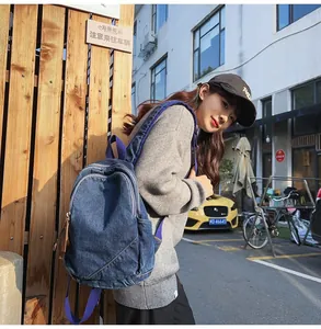 Detail of washed denim backpack with purple straps shown in a lifestyle street shot