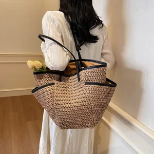 Handwoven straw tote bag with black leather straps and side pockets for beach travel