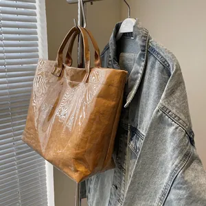 Detail view of the brown Dupont paper tote bag with transparent PVC overlay and OTE logo