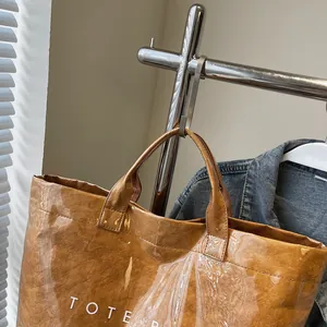 Detail view of the brown paper tote bag featuring waterproof PVC layer and white lettering