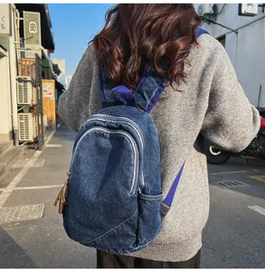 Detailed view of durable washed denim backpack with reinforced straps and zipper pockets