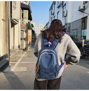 Detail of dark blue denim backpack with purple straps and leather zippers on a street