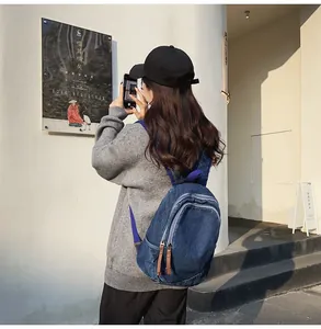 Close-up of vintage dark blue denim backpack featuring leather zipper pulls and front pocket