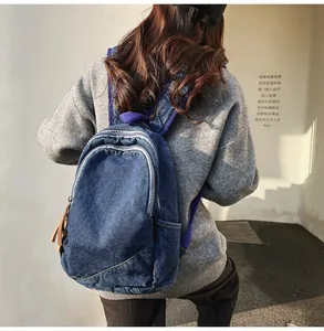 Blue denim backpack with brown fringe tassel and multiple zipper pockets shown on model