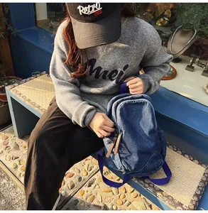 Outdoor shot of vintage washed denim backpack with dark blue fabric straps and brown zipper pulls