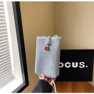 Detail of blue and white woven mini crossbody bag with a wooden flower button closure