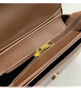 Close-up of smooth golden metal zipper and textured brown leather on women bag