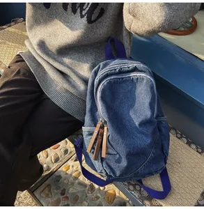 Detail of blue denim backpack with brown leather zipper pulls on a park bench