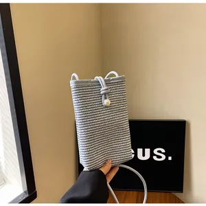 Detail of woven mini crossbody bag with drawstring closure and pearl accent