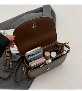 Detailed view of brown leather bag interior showing spacious storage for phones and makeup