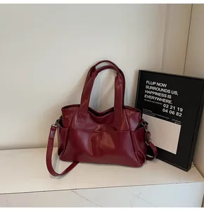 Macro detail of wine red tote bag showing faux leather texture and outer pockets