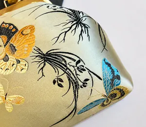 Vista detallada de bordados en seda champán con motivos de mariposas y cierre dorado