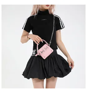 Pink mini crossbody bag with silver studs and metal chain shown on model in modern style