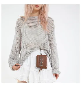 Close-up of a brown leather mini pouch bag with zipper and chain on a layered white skirt
