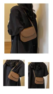 Detail view of brown saddle shoulder bag featuring gold buckle and adjustable strap