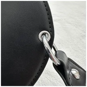 Detail view of silver metal ring and reinforced stitching on black leather guitar bag strap