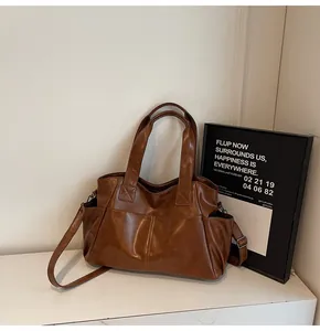Detail view of large brown tote bag showing dual front pockets and shoulder strap