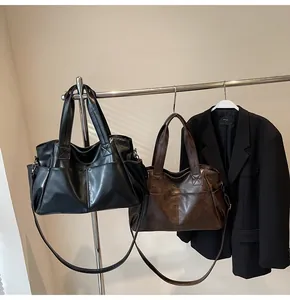 Detail view of large tote bags in black and dark brown with side pockets and shoulder straps