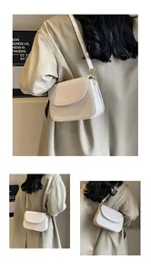 Close-up of beige leather crossbody bag with debossed lettering and gold hardware detail