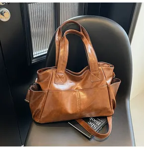 Detail view of large dark brown tote bag with retro PU leather texture on a chair