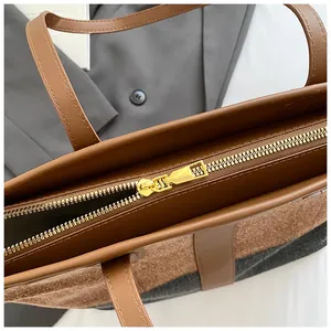 Détail de la fermeture éclair en métal doré sur le sac cabas bicolore en jean et cuir