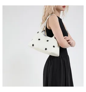 Detail der weißen Handtasche aus Leder mit silbernen Ösen und breitem Schultergurt-Design