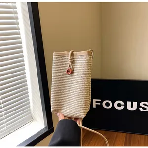 Close-up of woven straw mini bag with brown floral button and slim shoulder strap