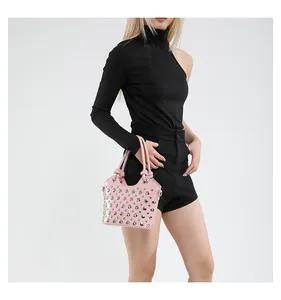 Borsa rosa stile punk con borchie argentate e dettaglio manico a nodo su una modella