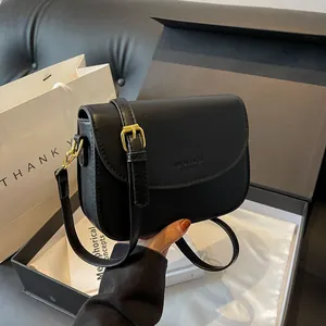 Minimalist black matte leather flap crossbody bag with golden buckle and adjustable strap