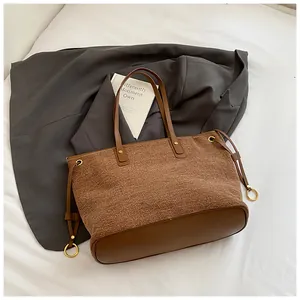 Détail du grand sac cabas en denim avec anses en cuir marron et anneau en métal doré
