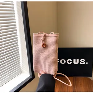 Detailed view of pink woven texture phone bag with wooden button and drawstring closure