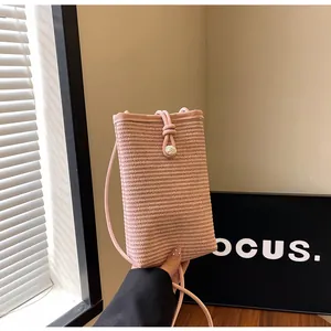 Detail of pink woven straw mini crossbody bag with pearl camellia button and drawstring