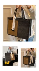 Dettaglio delle cuciture a contrasto e del tessuto materico della grande borsa in denim
