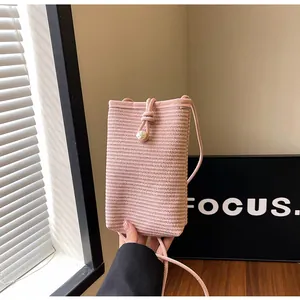 Detail of pink woven mini phone bag with pearl accent and minimalist shoulder strap