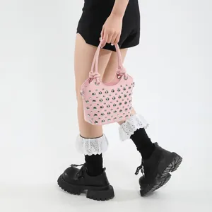 Borsa a secchiello in pelle rosa con borchie argentate e manici annodati su modella