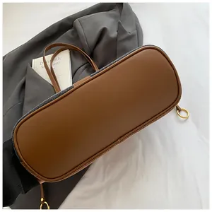 Gros plan sur la base en cuir marron renforcé et les coutures en laine grise du sac
